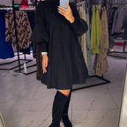 Close-up of bishop sleeve cuff on black pleated midi dress