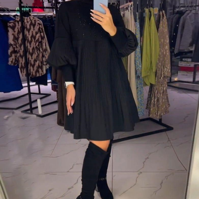 Close-up of bishop sleeve cuff on black pleated midi dress