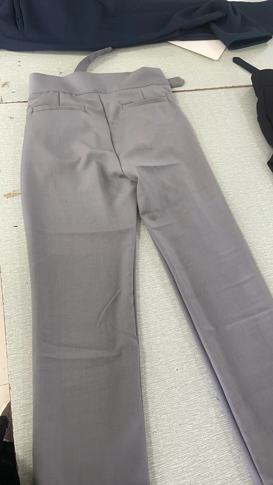Men's black pleated trousers with a high waist and adjustable tabs