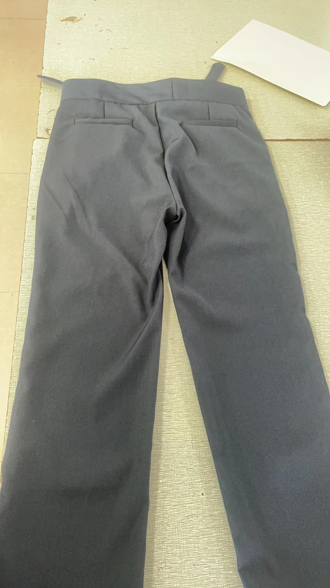 Men's black pleated trousers with a high waist and adjustable tabs