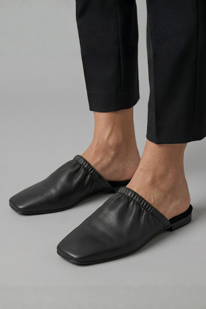 Black leather mules with cap toe and slip-on fit