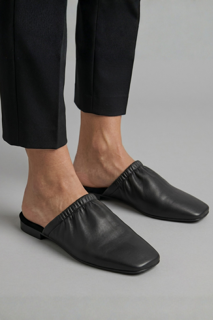 Black leather mules with cap toe and slip-on fit